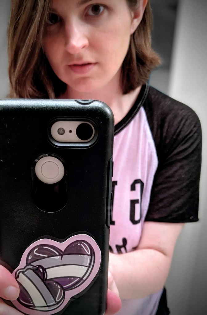 Selfie of a girl with an asexual heart sticker on a phone case
